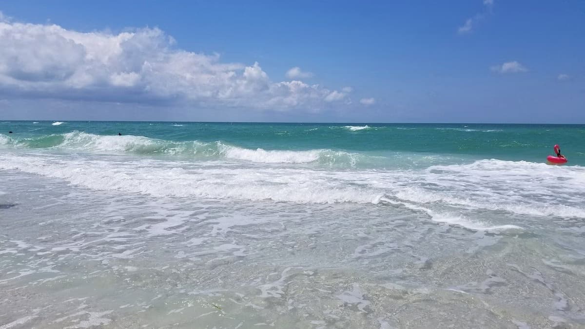 Rolling waves in green-blue water under white clouds